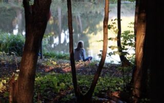 Woman sits by lake